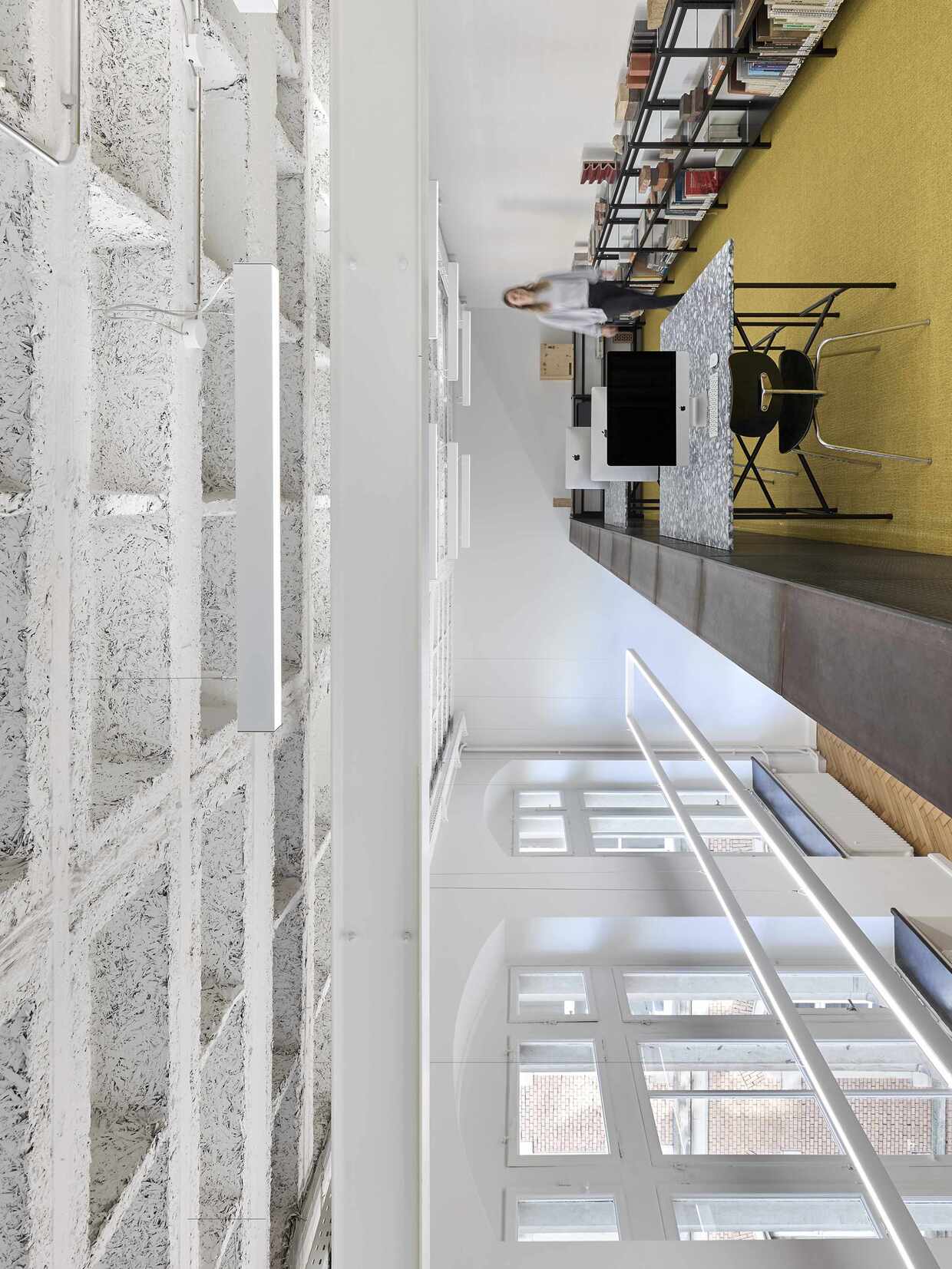 Modernes Büro mit Computern, Regalen und großen Fenstern.